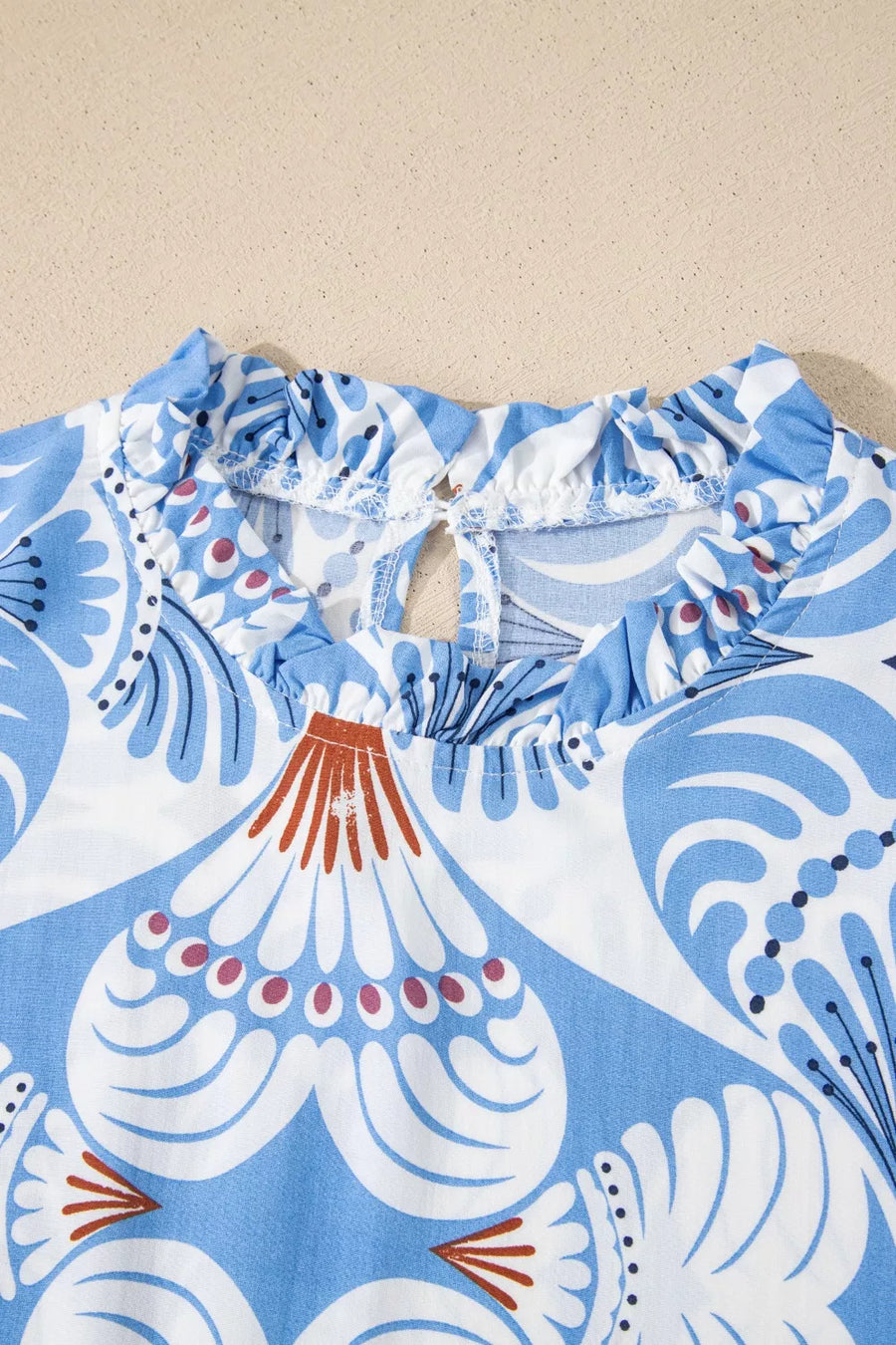 Blue and white botanic print dress with ruffled neckline and keyhole back detail.