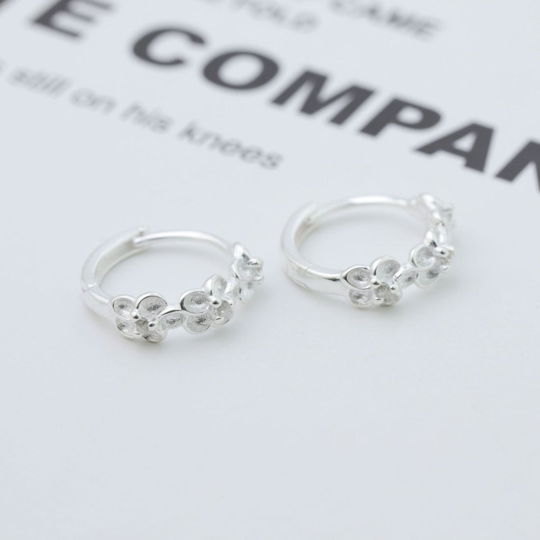 earrings in silver featuring floral embellishment and hoop fit