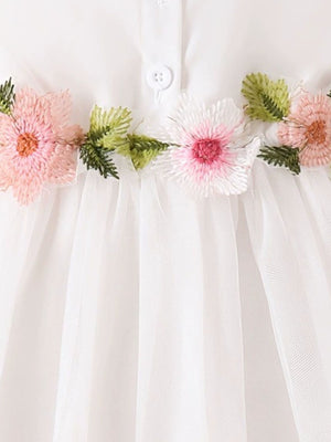 White baby dress with floral appliqué detail and button front.