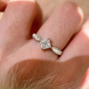 Sterling silver ring with princess-cut moissanite and geometric band.