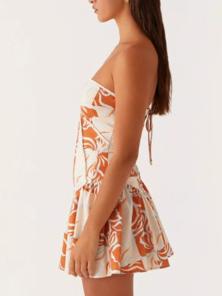 Ruffled tube dress with floral print and back tie detail in cream and orange.