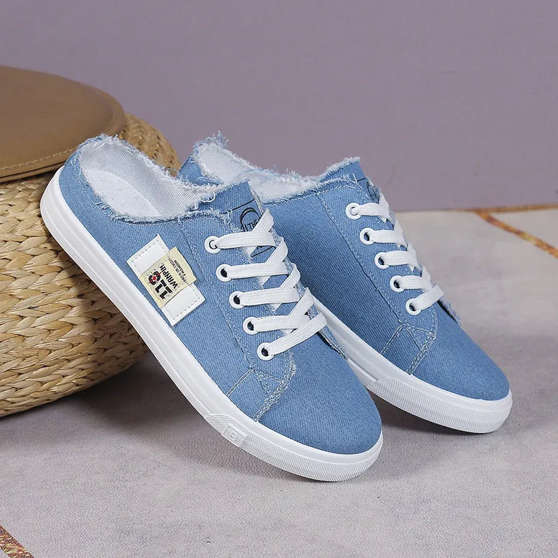 Light blue denim mule sneakers with raw edges and white laces.