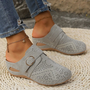 Gray laser-cut buckle mule wedges with perforated details and adjustable strap.