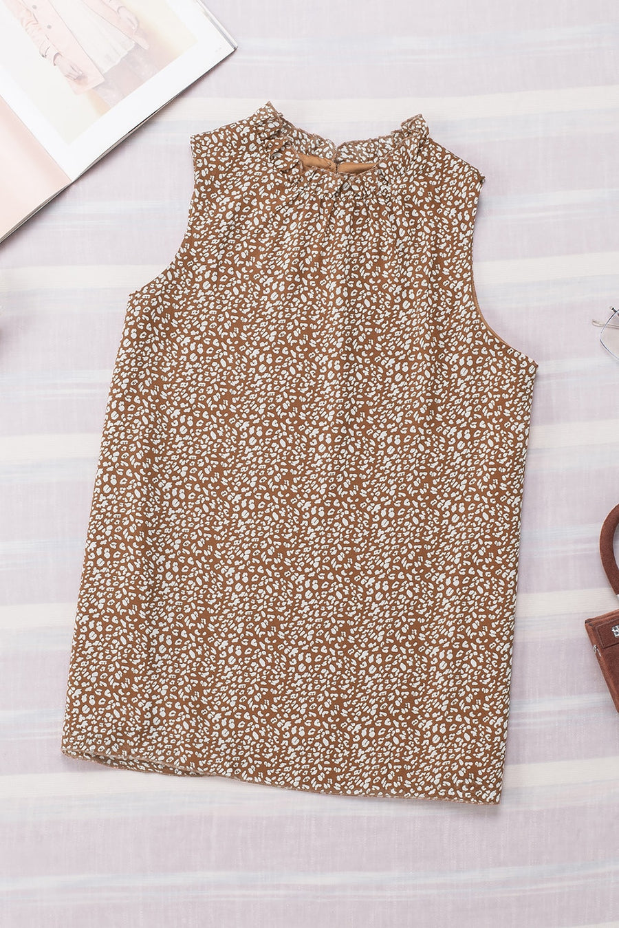 Brown printed sleeveless blouse with ruffled neckline and tie detail.