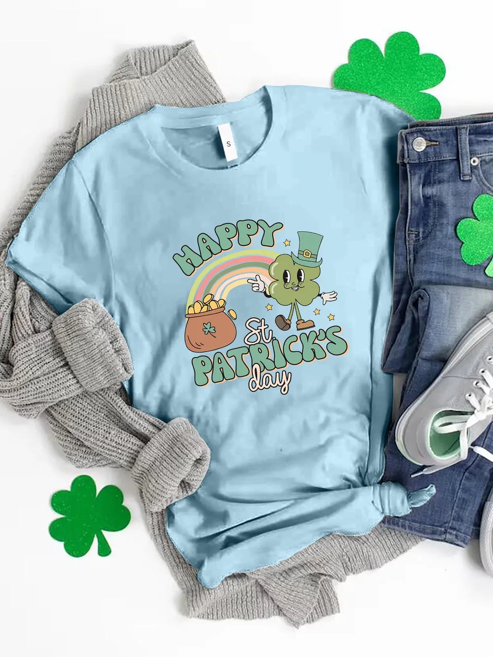 Light blue St. Patrick's Day graphic t-shirt with a cartoon clover, rainbow, and pot of gold.