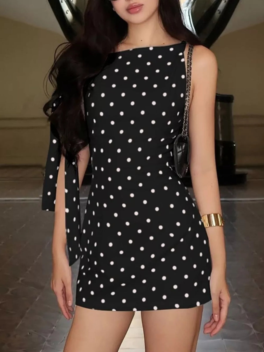 Black polka dot mini dress with asymmetrical neckline and bow sleeve details.