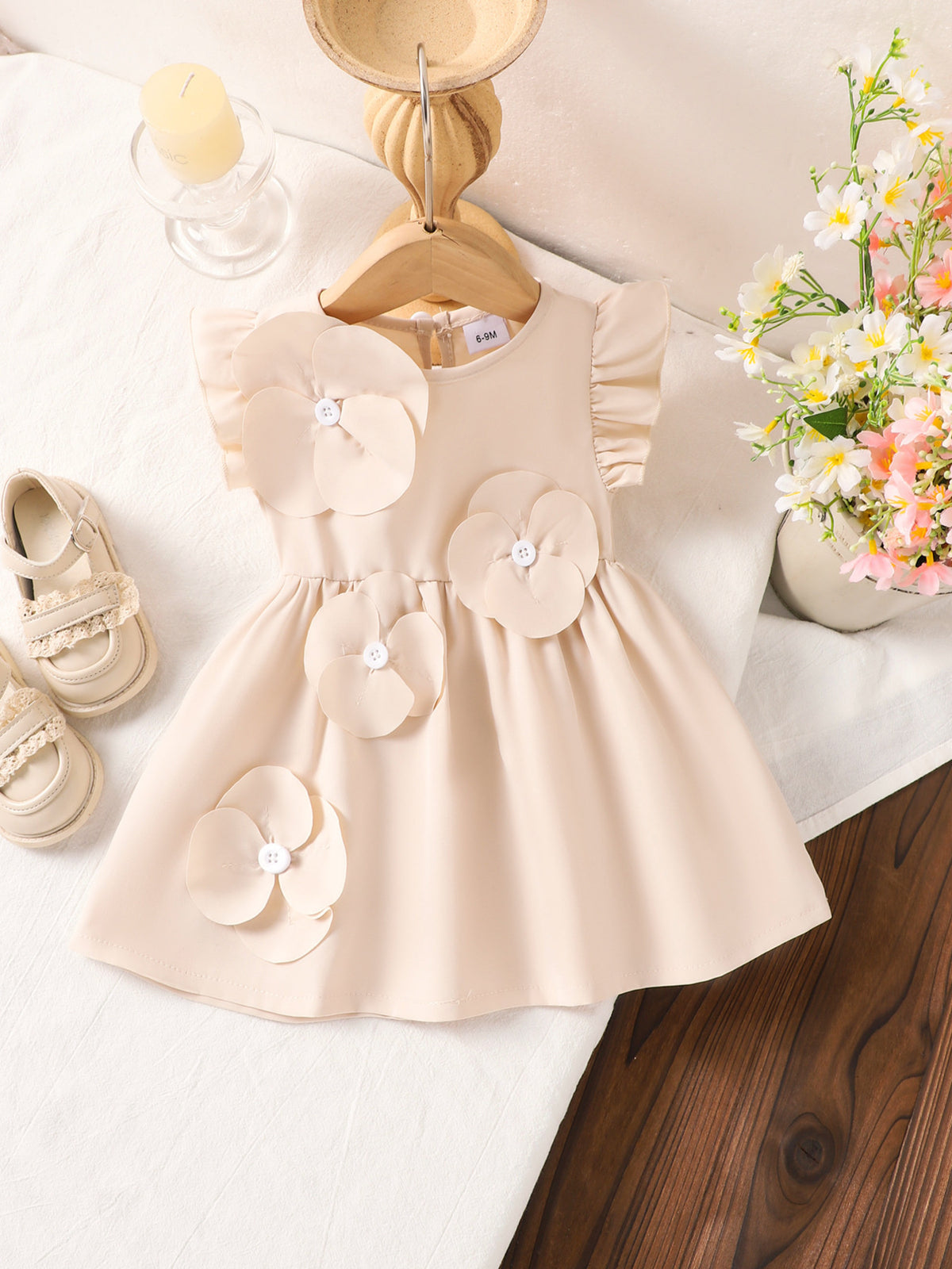 Off-white baby dress with ruffle sleeves and 3D flower appliqués.