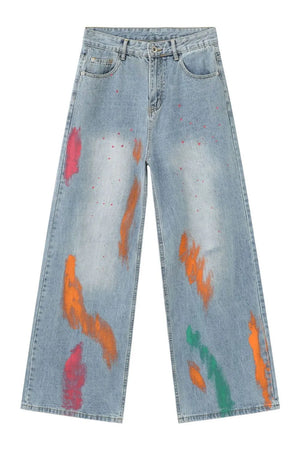 Painterly wide-leg denim jeans in light wash with abstract paint splatters and strokes in pink, orange, and green.