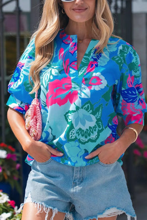 Vibrant floral print V-neck blouse with relaxed fit and short sleeves, styled with denim shorts.