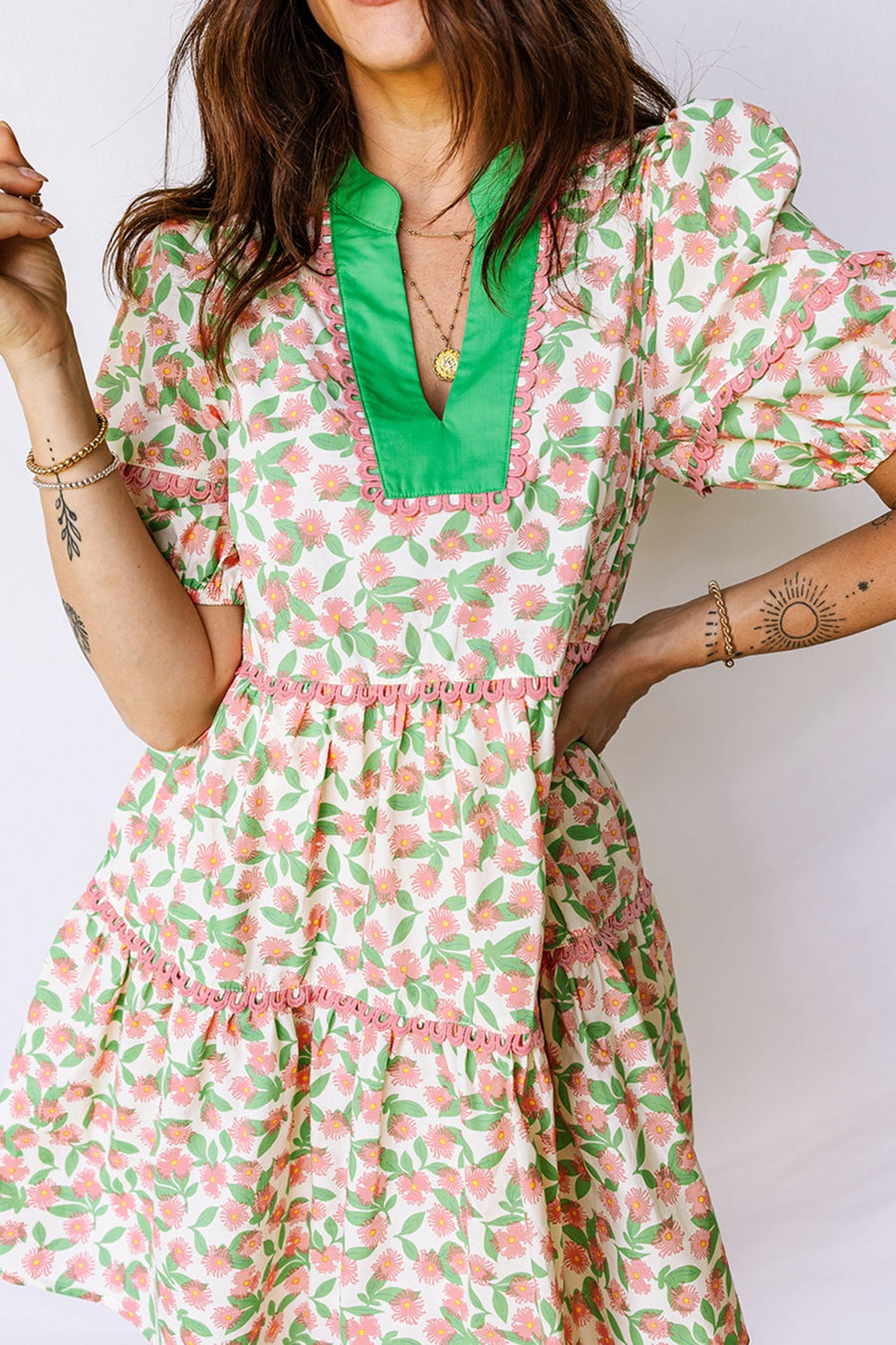 Women's tiered mini dress with pink floral print, green collar, and puff sleeves.