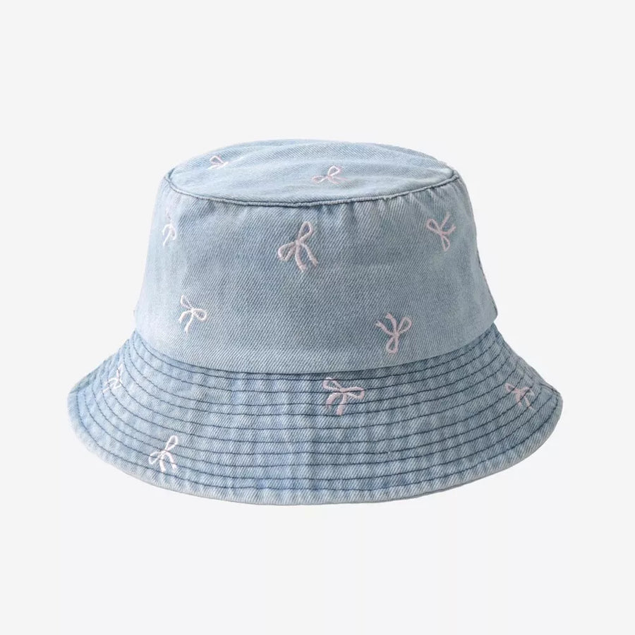 Denim bucket hat with all-over pink bow embroidery and a striped brim.