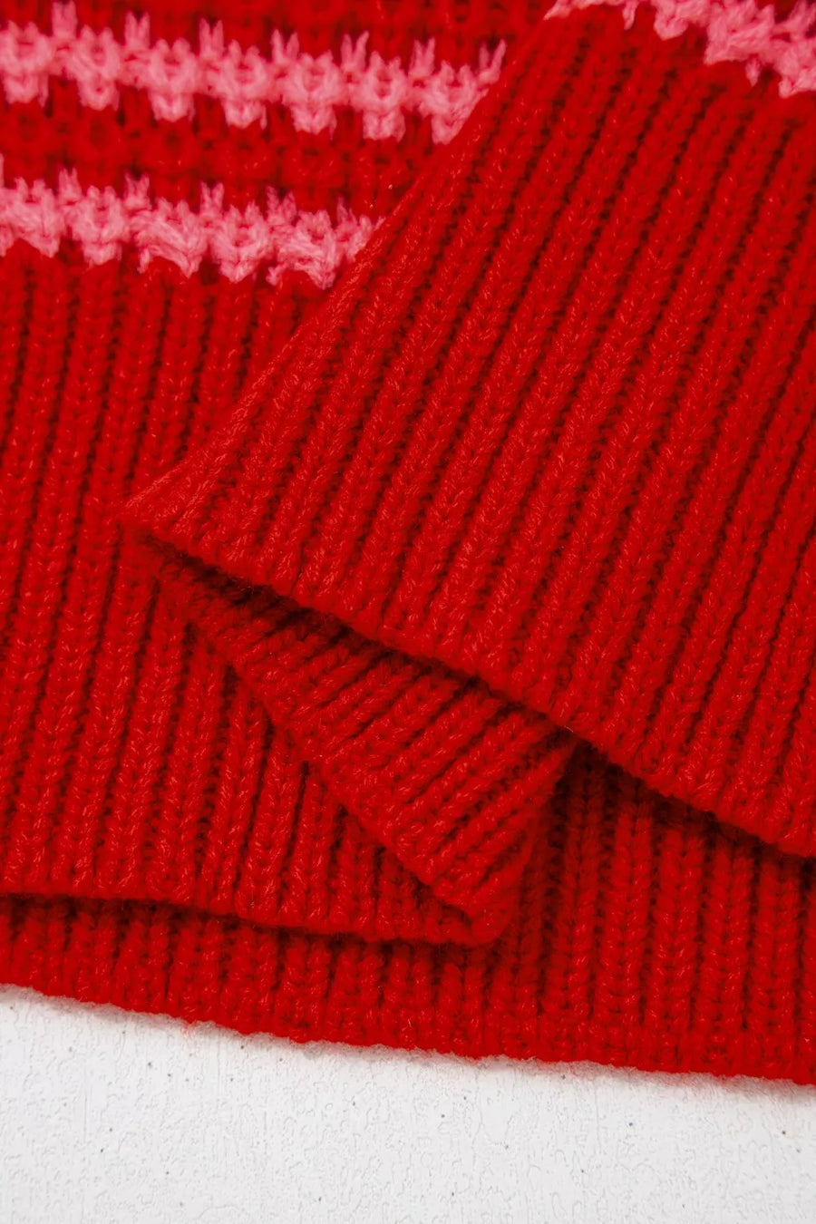 Red acrylic knit sweater with wavy crochet detail and ribbed texture.