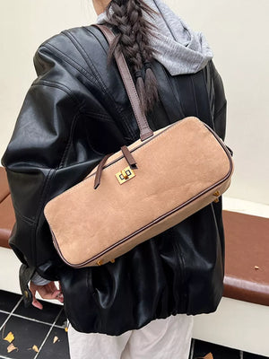 Khaki suede shoulder bag with gold clasp and brown trim, worn crossbody.