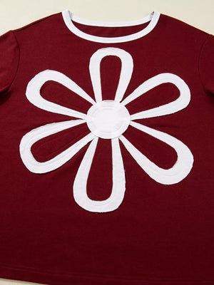 Burgundy long-sleeve top with white flower patch detail and white trim neckline.