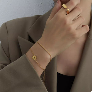 Gold double layered titanium steel bracelet with circular charm and adjustable chain