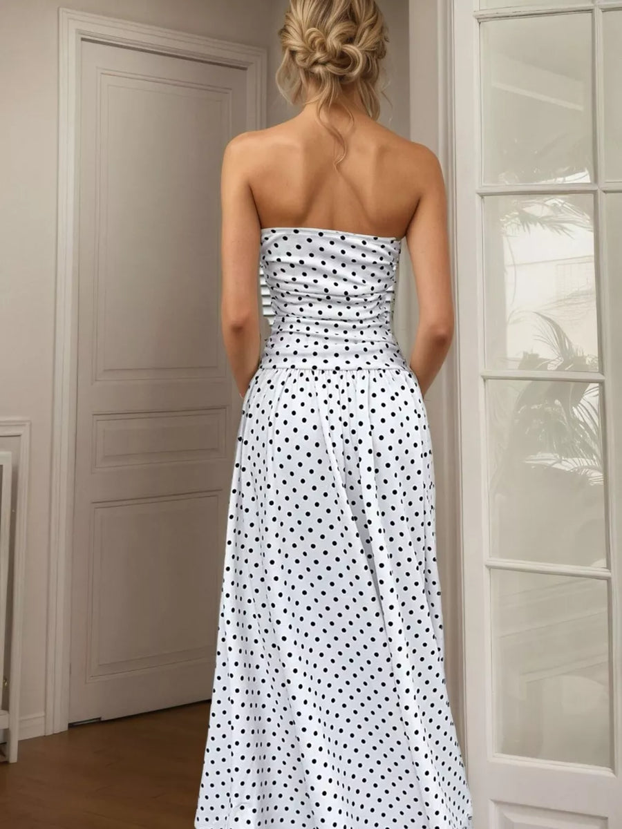 White polka dot strapless maxi dress with ruched bodice and flowing skirt.