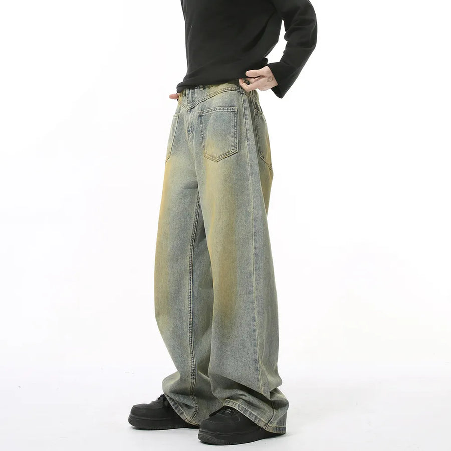 Distressed denim jeans in medium wash with yellowing accents, wide leg, and cotton composition.