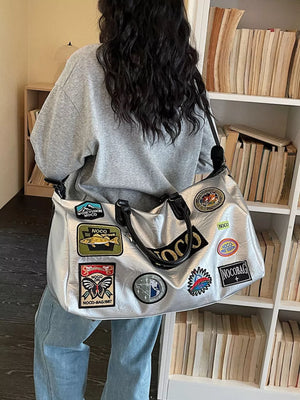 Metallic patchwork travel bag with textured finish and embroidered patches.