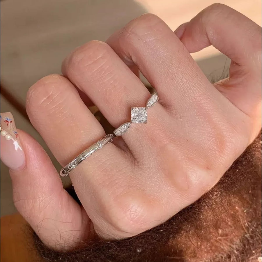 Sterling silver ring with moissanite center stone and geometric band detail.