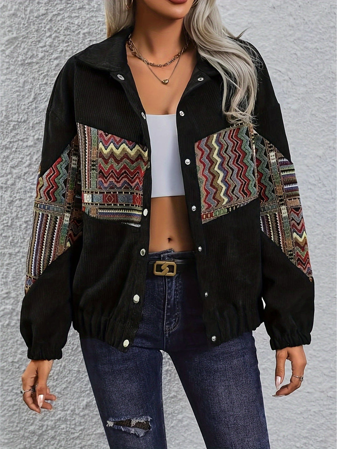 Black corduroy bomber jacket with colorful geometric patchwork on sleeves and chest.