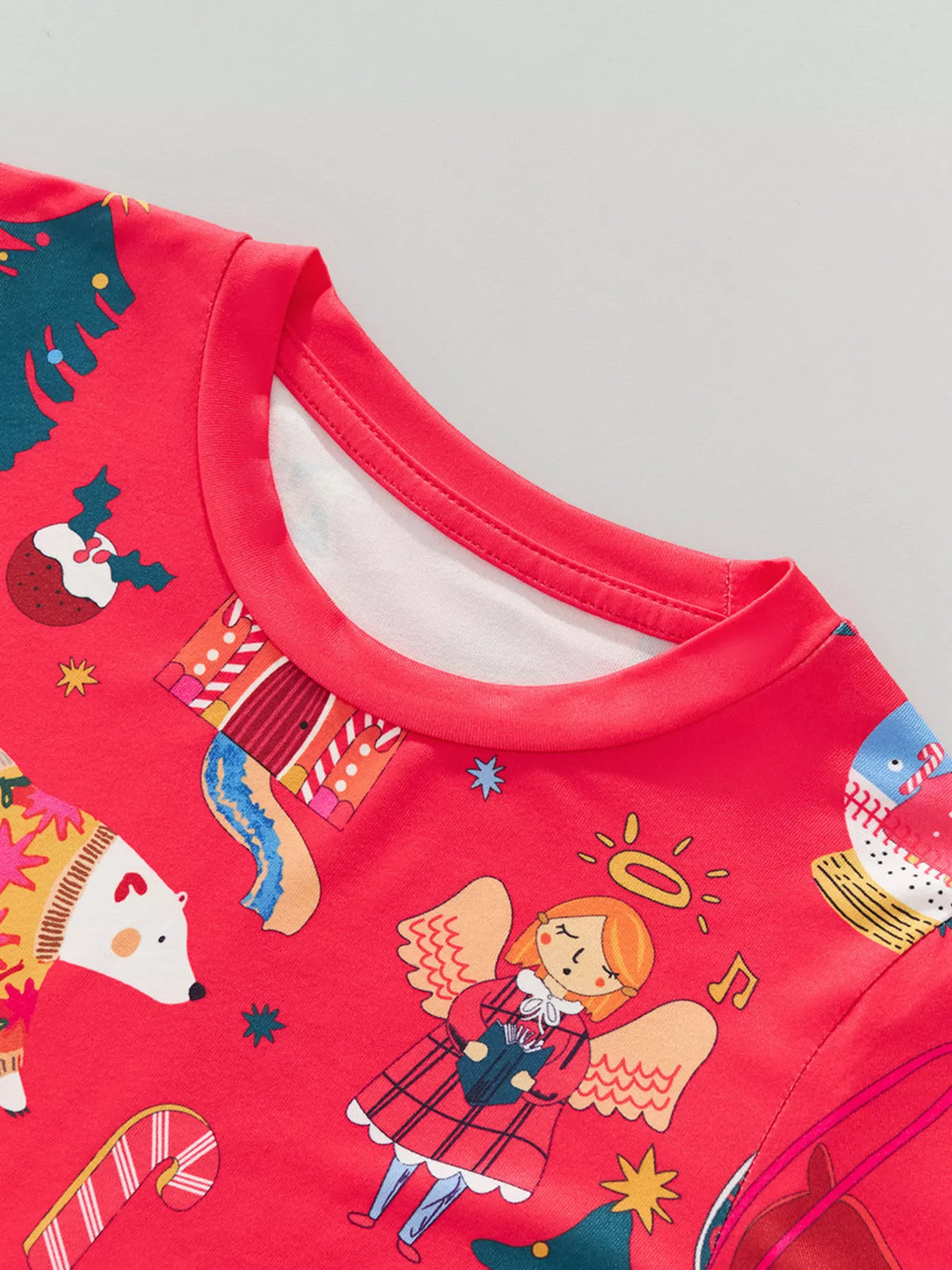 Children's red Christmas pajama top with festive print including angels, polar bears, and candy canes.