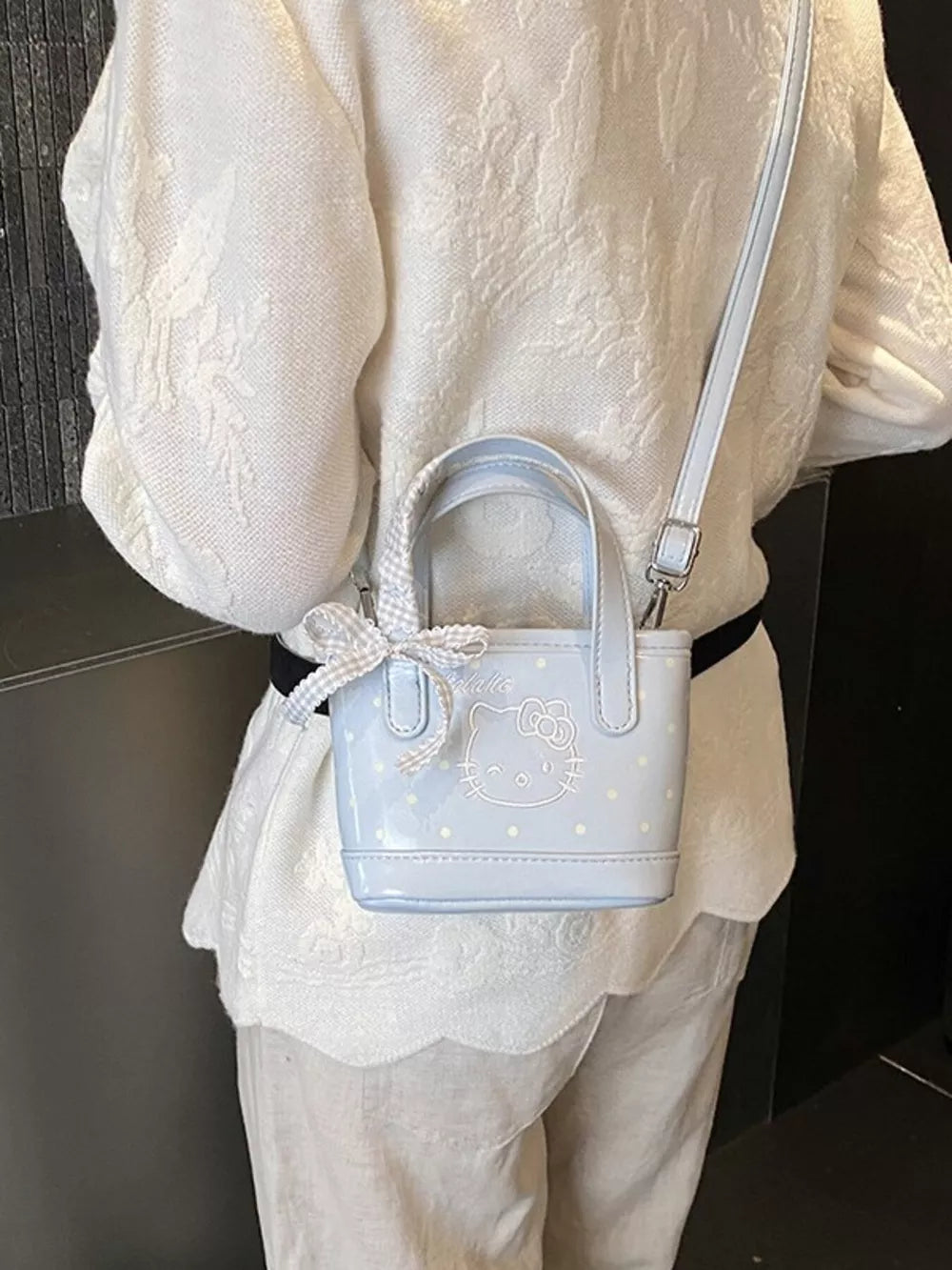 Light blue mini crossbody bag with Hello Kitty graphic and bow detail.