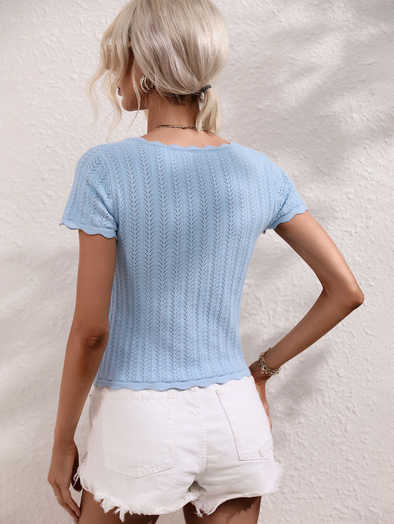 Light blue knit top with scalloped neckline and hem, featuring a textured pattern.