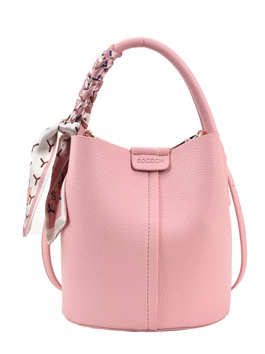Pink pebbled leather bucket crossbody bag with braided handle and printed scarf detail.