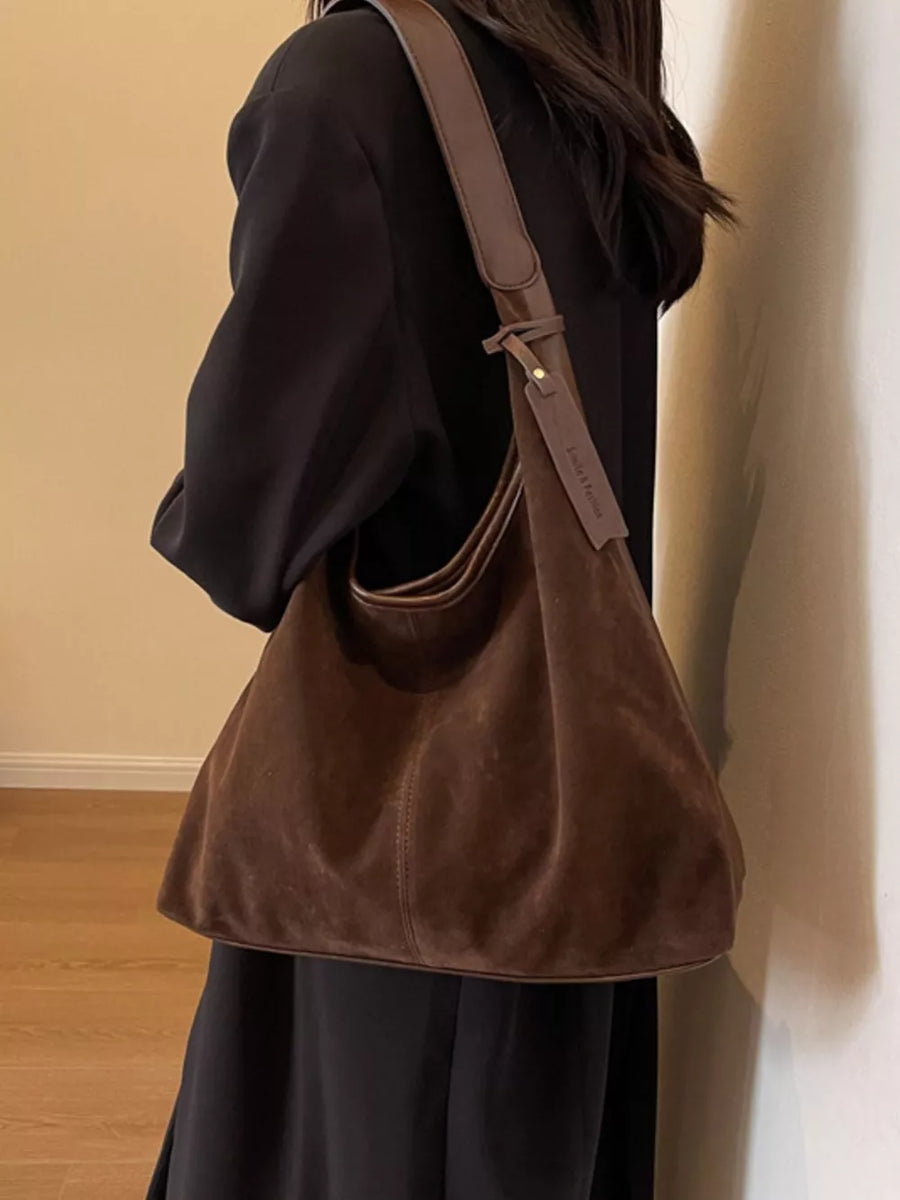 Brown plush corduroy hobo shoulder bag with leather strap detail.