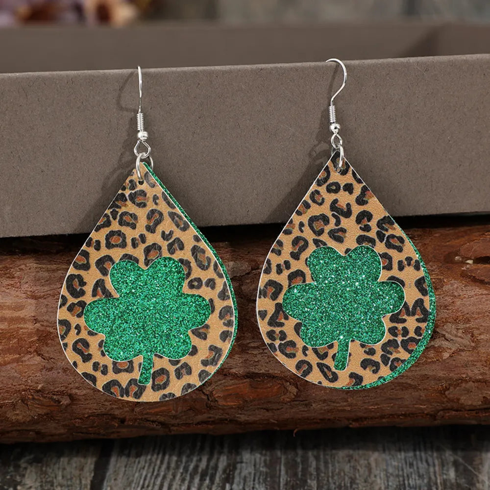 Leopard print teardrop earrings with green glitter shamrock cutouts.