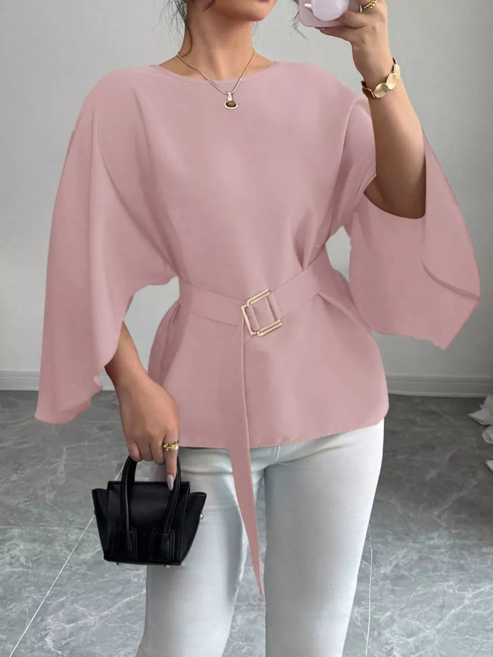 Pink belted blouse with batwing sleeves and gold buckle detail.