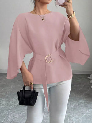 Pink belted blouse with batwing sleeves and gold buckle detail.