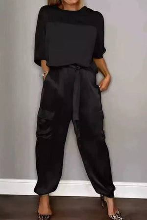 Black satin two-piece ensemble with a belted cargo pant and short-sleeve top.