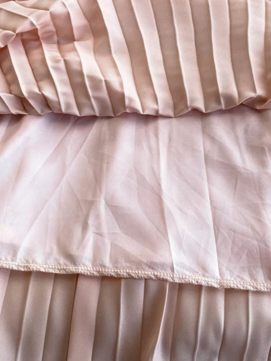 Pink pleated maxi dress with satin finish and sheer overlay detail.