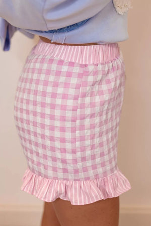 Blush pink gingham cotton shorts with ruffle hem and drawstring waist.