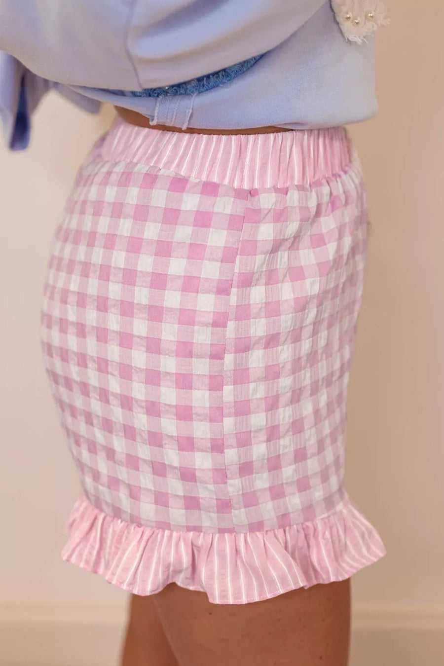 Blush pink gingham cotton shorts with ruffle hem and drawstring waist.