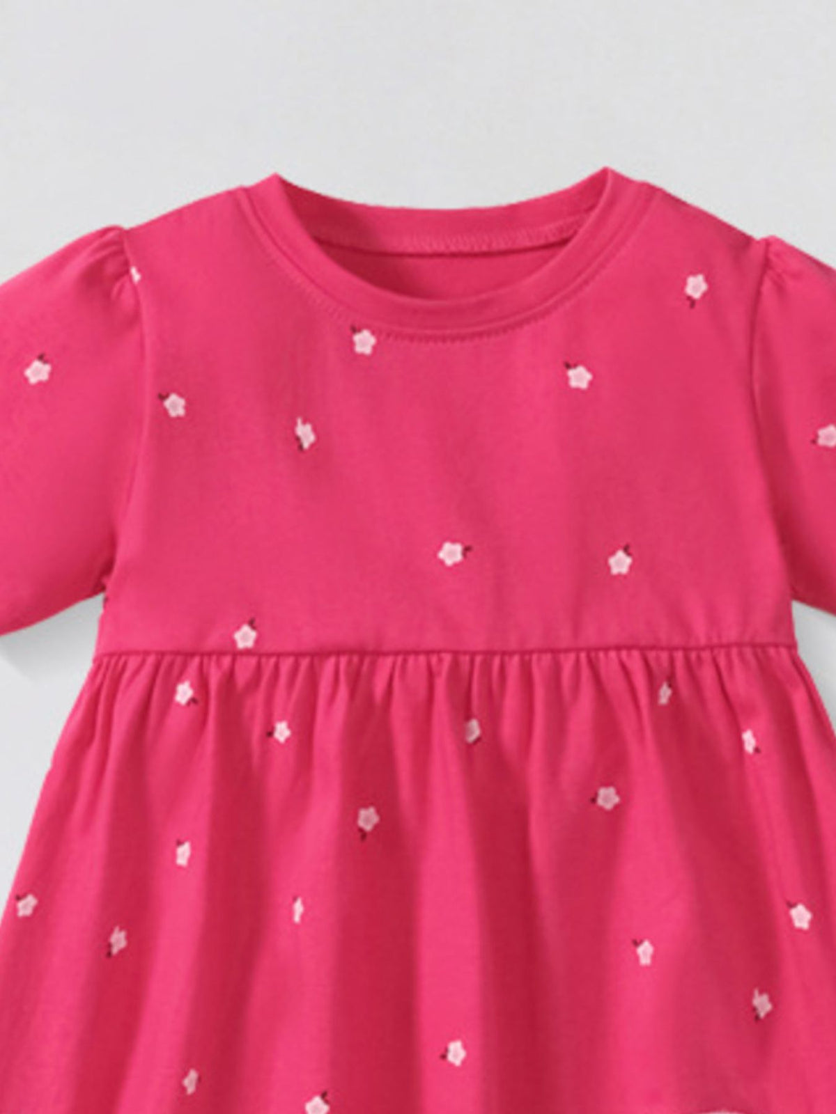 Toddler pink cotton dress with scattered white flower applique and puff sleeves.