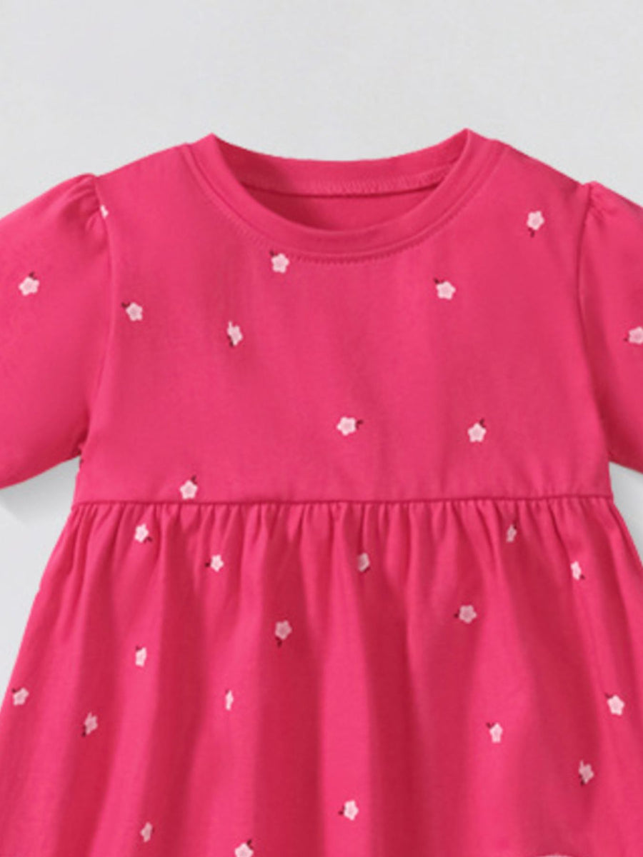 Toddler pink cotton dress with scattered white flower applique and puff sleeves.