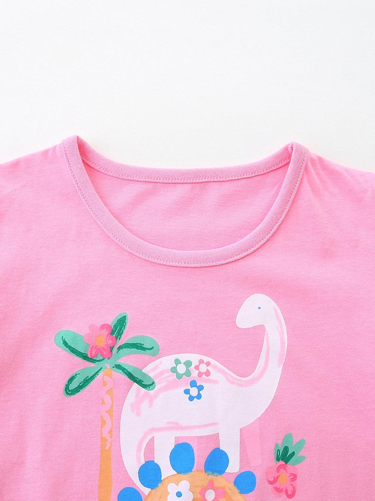 Pink cotton crew neck t-shirt with a playful dinosaur and floral print.