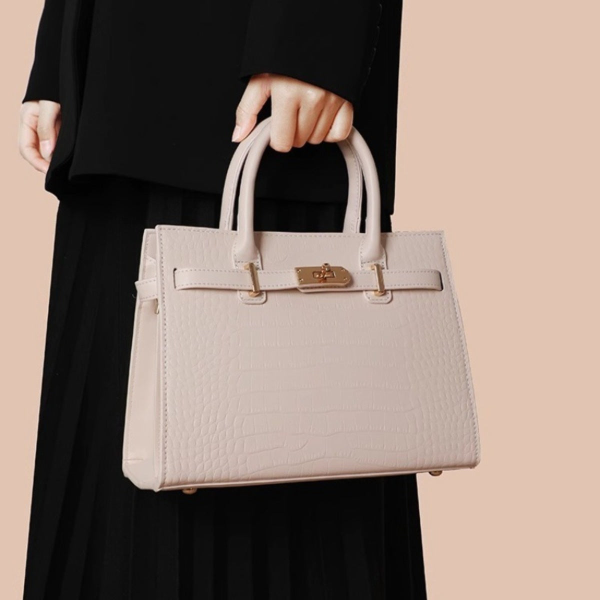Crocodile-embossed medium tote handbag in Rice White with gold hardware and top handles.