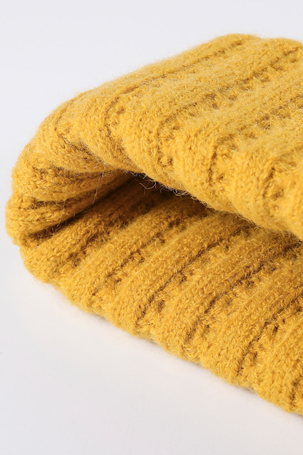 Textured ribbed knit beanie in mustard yellow acrylic with a folded brim detail.