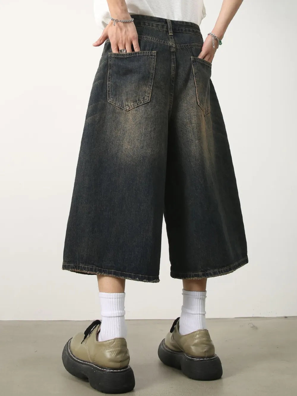 Wide-leg distressed denim culottes in dark wash with a relaxed fit and frayed hem.