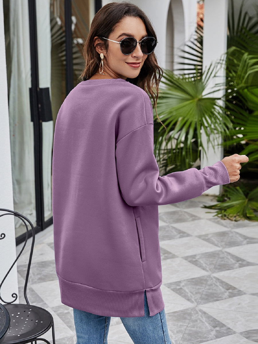 Purple tunic sweatshirt with side pockets and a rounded hem.