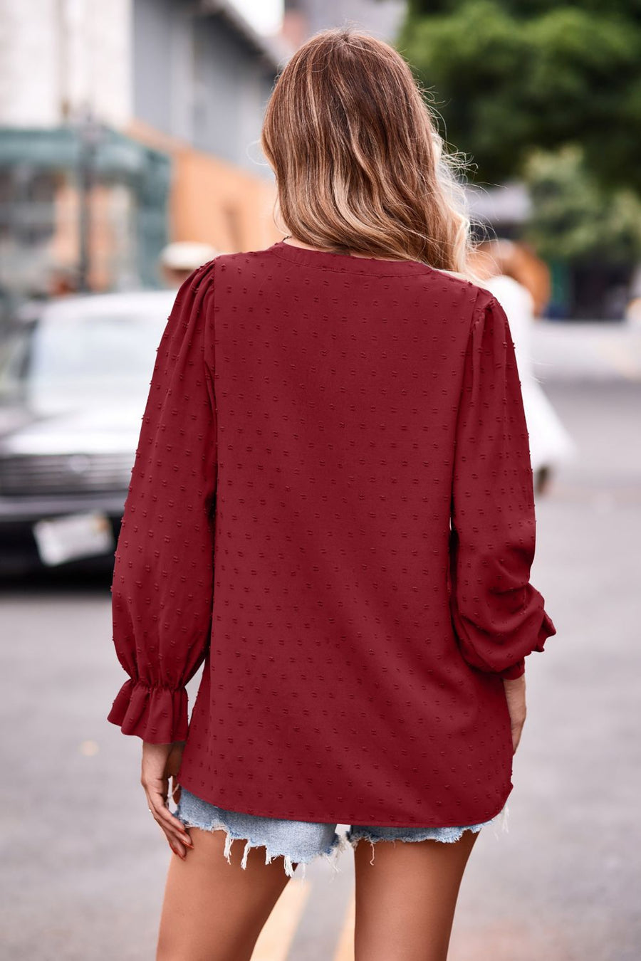Burgundy textured dot v-neck blouse with ruffle cuffs and long puff sleeves.