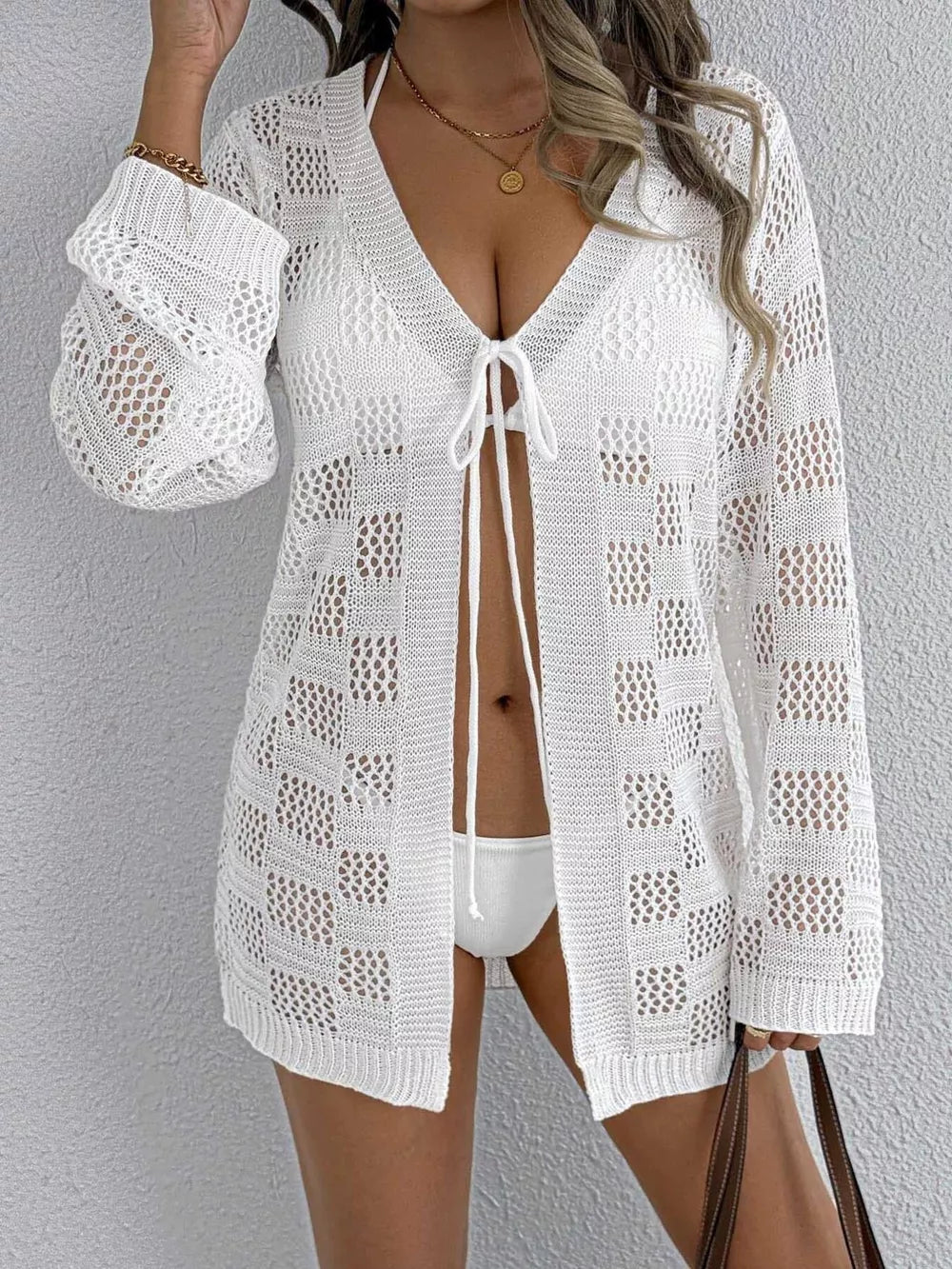 White openwork crochet tie-front cover-up with V-neck and long sleeves.