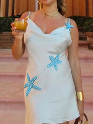 White slip dress with blue starfish embellishments and cowl neck.
