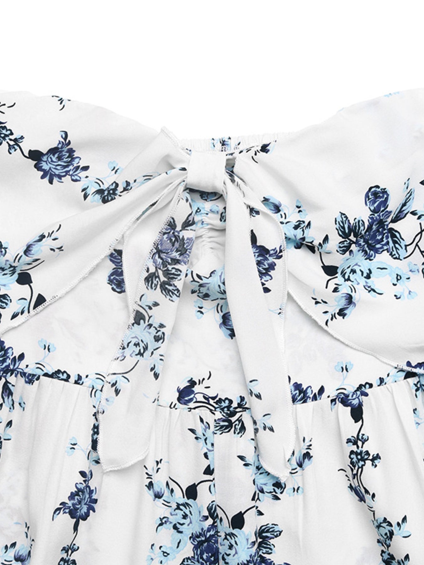 White floral romper with blue flowers, smocked back and tie-front detail.