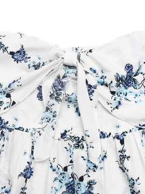 White floral romper with blue flowers, smocked back and tie-front detail.