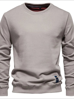 Gray crewneck sweatshirt with subtle patch detail and ribbed cuffs and hem.