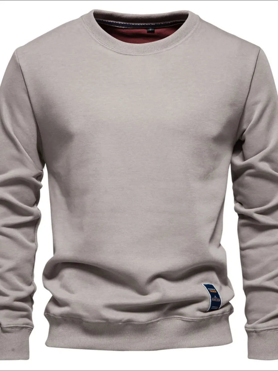 Gray crewneck sweatshirt with subtle patch detail and ribbed cuffs and hem.